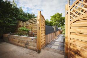 Property, home and exterior of backyard, entrance and door by architecture with walkway. Residential real estate, house or garden fence, trees or path by building patio outdoor on landscape in summer