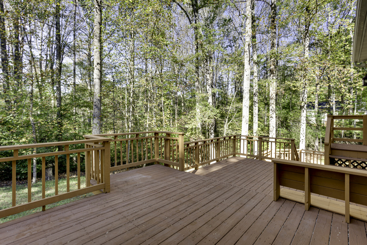 A large wooden deck provides an expansive view of a lush forest, creating a serene and natural atmosphere, perfect for relaxation and outdoor gatherings.